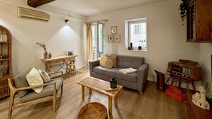 Een gezellige woonkamer met een houten vloer, een grijze bank, een houten salontafel en een boekenkast.