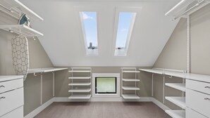 Un vestidor amplio con estanterías integradas, un ventanal pequeño y un ventilador de techo.