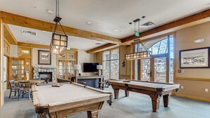 A pool area with wooden pool tables, a stone fireplace, and large windows. - ★★ KEYSTONE CONDO ★★ Ski in/out - RiverRun Village 1BD 1BA (Keystone)