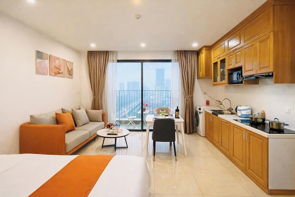 Une chambre d’hôtel comprenant un lit, un canapé, une table à manger avec des chaises, un coin cuisine et un balcon avec vue sur la ville.