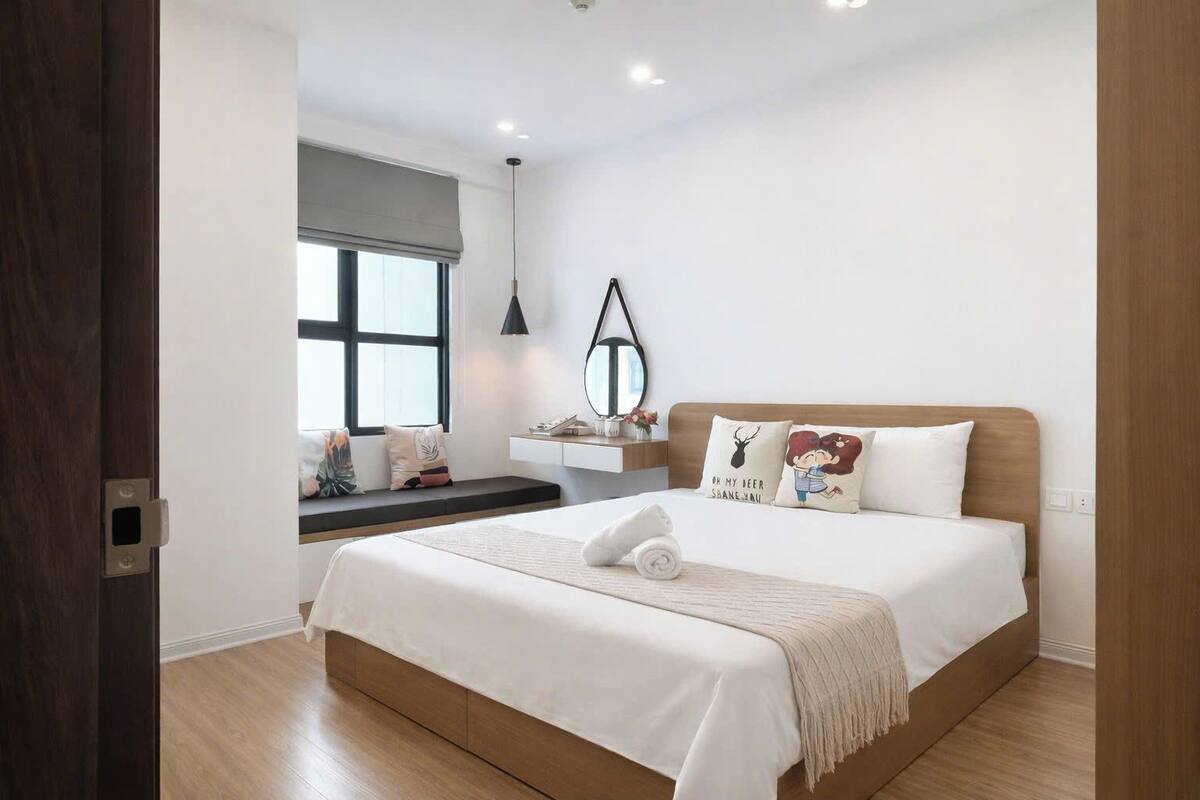 Une chambre à coucher avec un lit, une table de chevet, une fenêtre et un miroir.