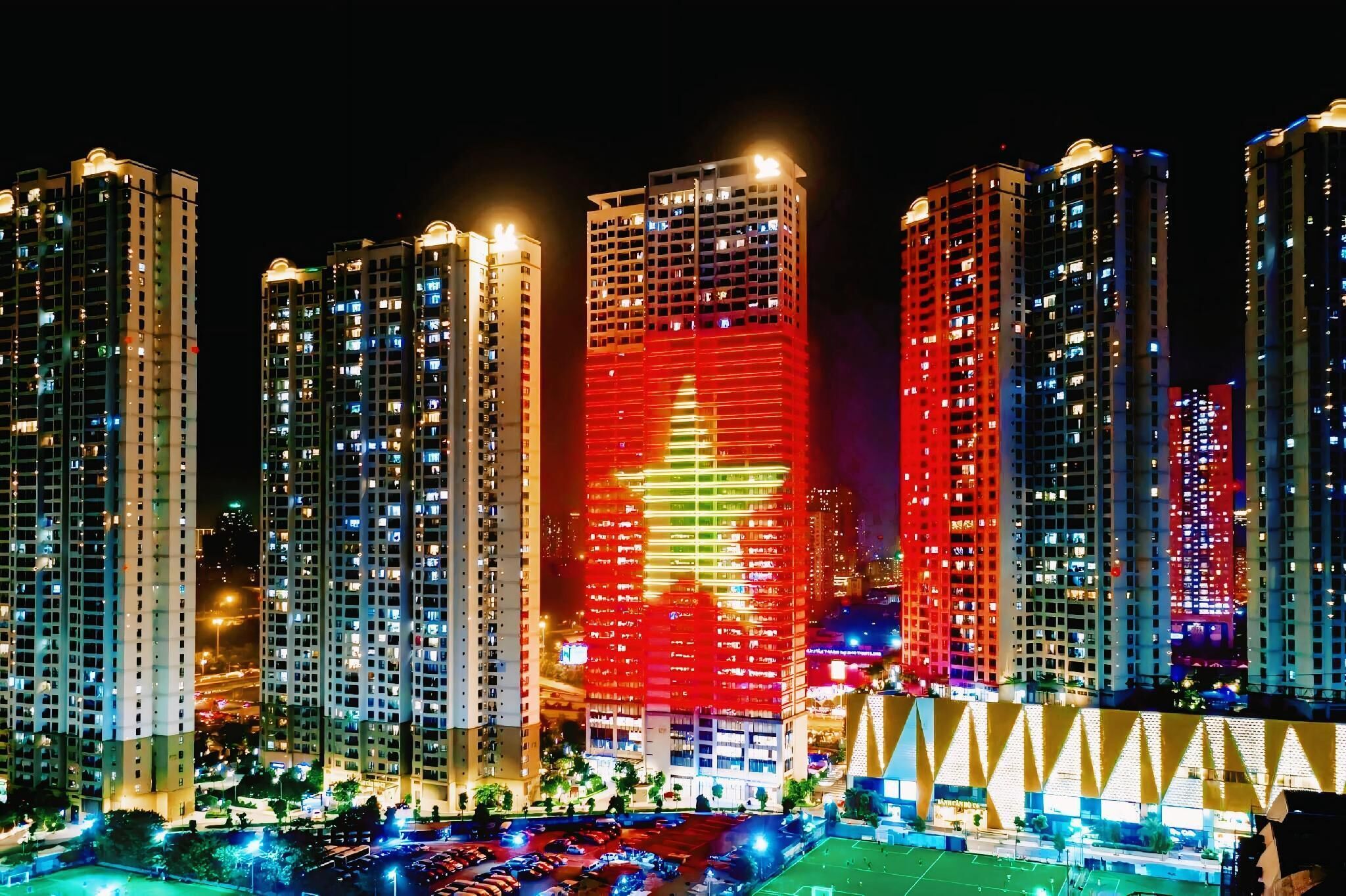 A nighttime view of high-rise buildings with illuminated windows and a prominent building with a red star.