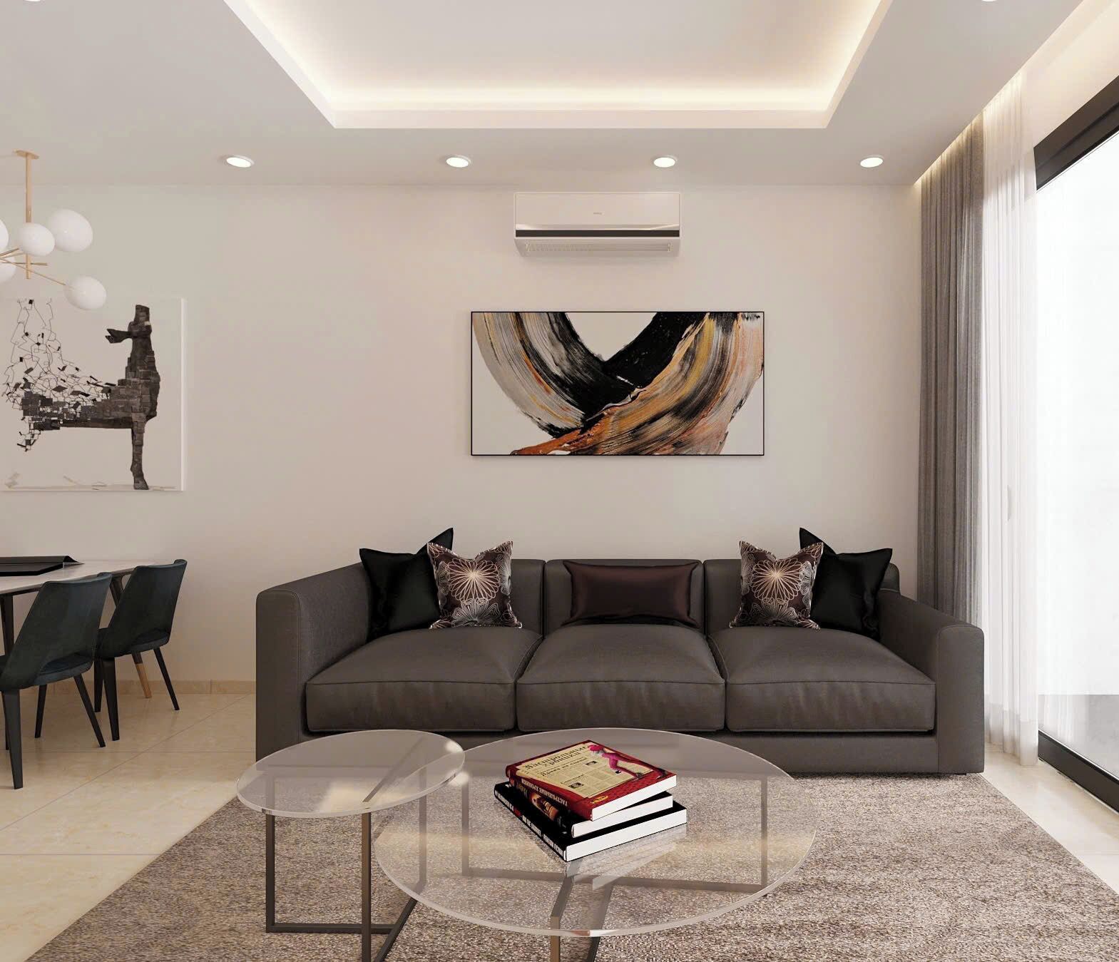 Ein modernes Wohnzimmer mit einem grauen Sofa, einem Glastisch und einem Gemälde an der Wand.