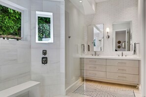 Une salle de bain moderne avec une douche, un meuble-lavabo avec un miroir et un banc.