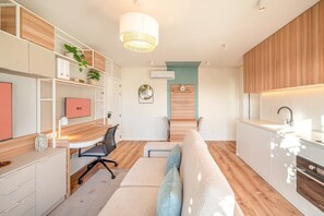 Eine moderne Küche mit Einbauofen, ein Essbereich mit Holztisch und -stühlen sowie eine gemütliche Sitzecke mit Sofa und Kissen.