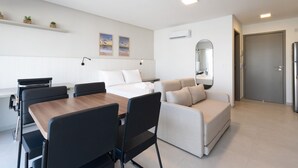 A modern hotel room with a dining area, a sofa, a bed, and a small balcony. - Icon Housi in Boa Viagem New 300m From the Sea By Carpediem (Recife)