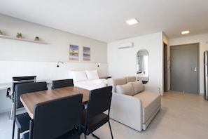 A modern hotel room with a dining area, a sofa, a bed, and a small balcony. - Icon Housi in Boa Viagem New 300m From the Sea By Carpediem (Recife)