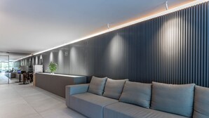 Een moderne receptie met een grijze bank, een receptiebalie en een verticale paneelwand.