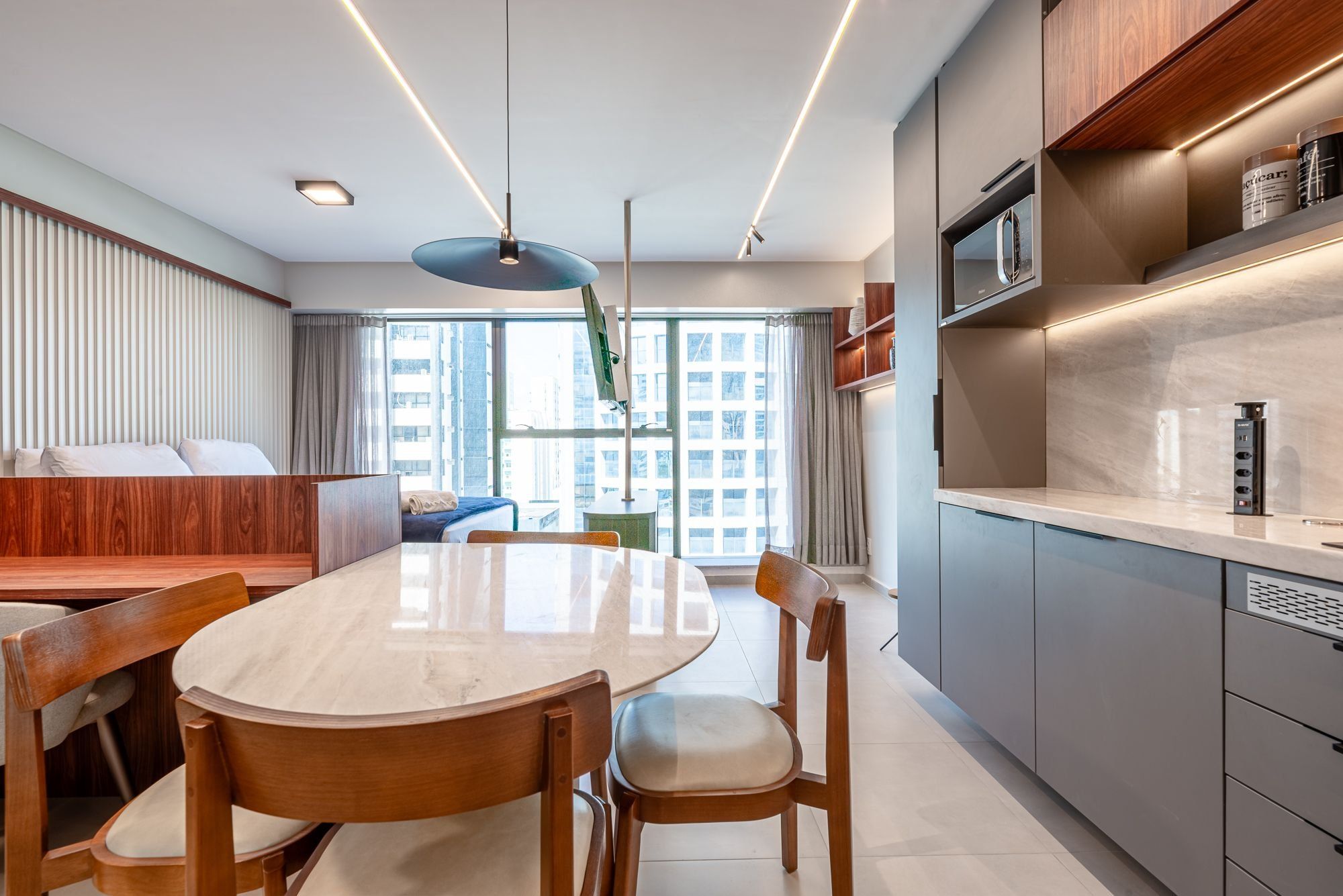 A modern kitchen with a marble countertop, wooden chairs, and a dining table.
