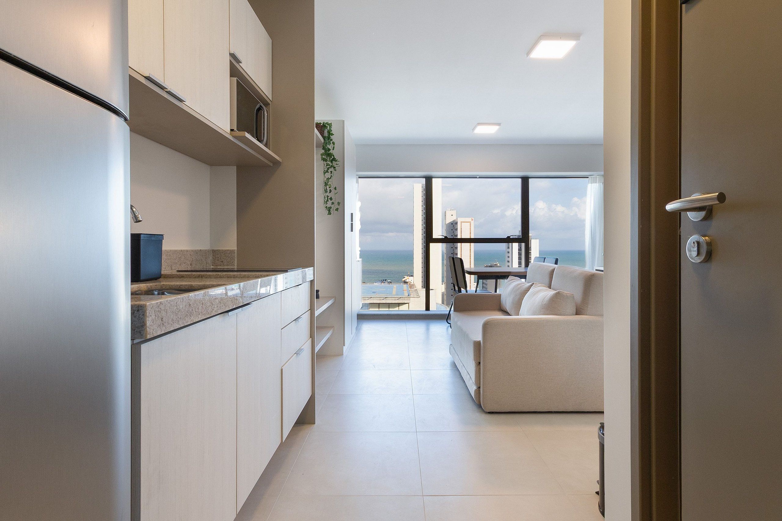 Una cocina moderna con vista al mar, una sala de estar con sofá y una puerta con cerradura de llave.