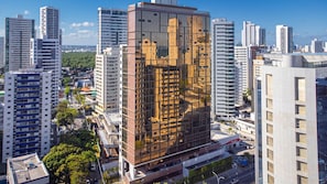 Un immeuble moderne de grande hauteur, doté d’une façade originale, et entouré d’autres immeubles de grande hauteur dans un environnement urbain.