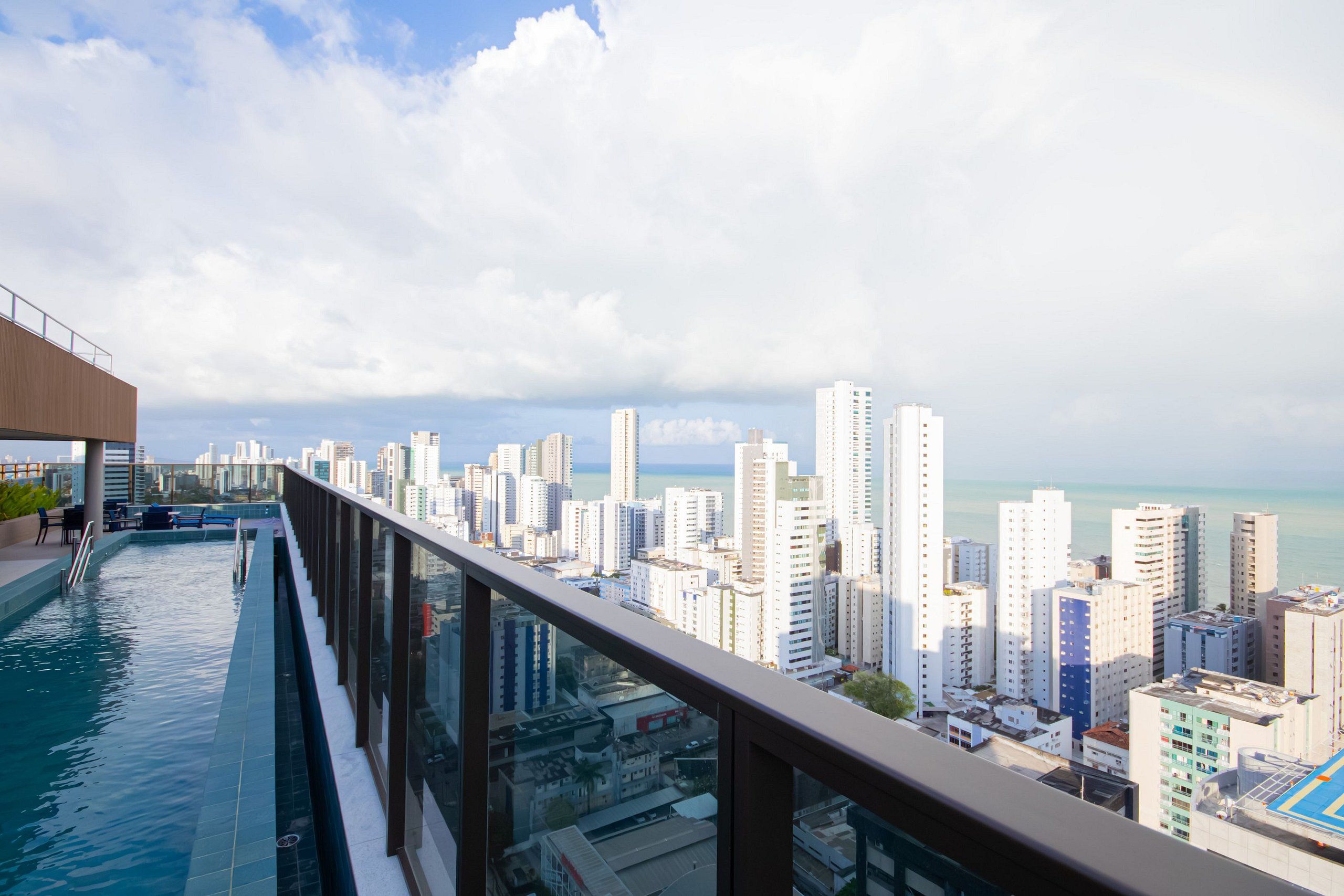 A rooftop infinity pool with a city view, modern architecture, and a clear sky.