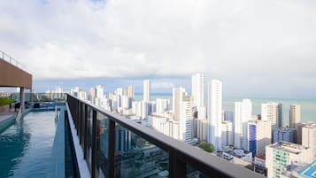 Une piscine à débordement située sur le toit, offrant une vue sur la ville, une architecture moderne et un ciel dégagé.