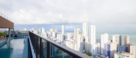 A rooftop infinity pool with a city view, modern architecture, and a clear sky.