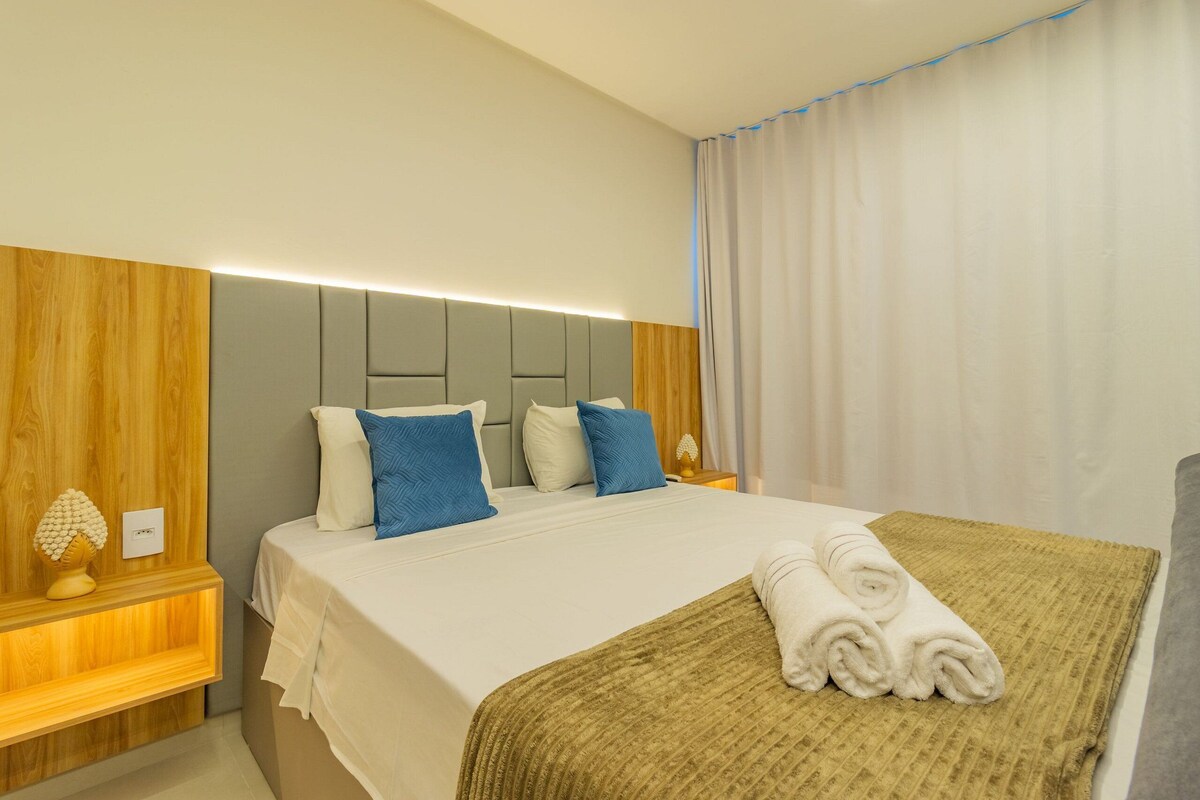 Une chambre d’hôtel avec un lit, une table de chevet, une lampe et une fenêtre avec des rideaux.