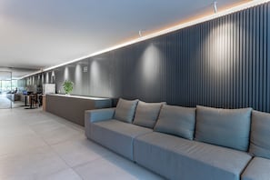 Un espace d’accueil moderne avec un canapé gris, un comptoir d’accueil et un mur décoratif vertical.