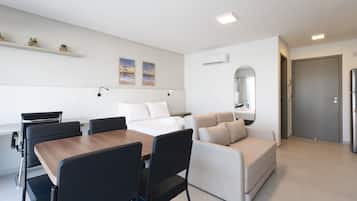 Una habitación de hotel moderna con comedor, sofá, cama y un pequeño balcón.