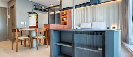 A modern hotel room with a dining area, a bed with a headboard, and built-in storage.