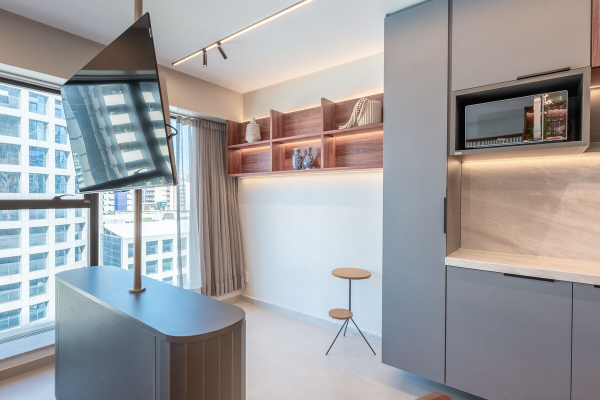 Een moderne keuken met een ingebouwde magnetron, houten planken en een kleine ronde tafel.