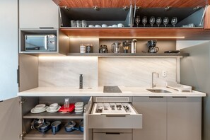 A compact kitchenette with a built-in coffee maker, a microwave, and a drawer with utensils.