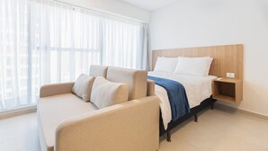 A hotel room with a bed, a sofa, a nightstand, and a window with sheer curtains. - Icon Housi in Boa Viagem New 300m From the Sea By Carpediem (Recife)