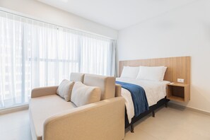 A hotel room with a bed, a sofa, a nightstand, and a window with sheer curtains. - Icon Housi in Boa Viagem New 300m From the Sea By Carpediem (Recife)
