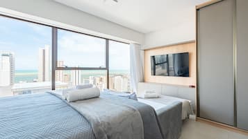 Quarto de hotel moderno com uma cama grande, uma televisão e vista para a cidade.