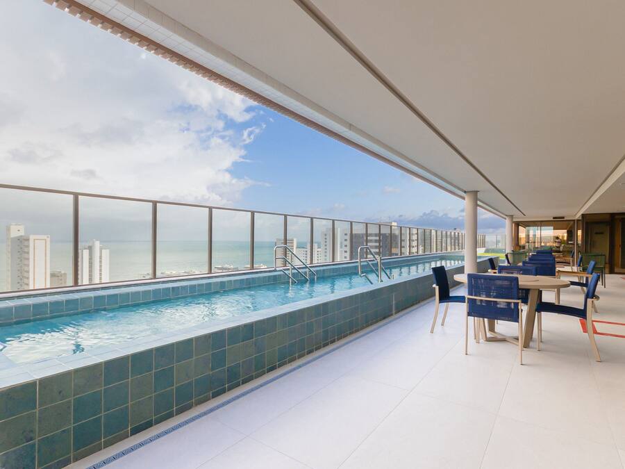 A rooftop pool with a view of the city skyline and a dining area with tables and chairs.