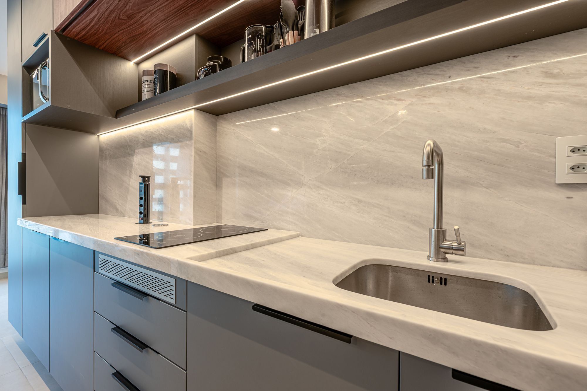 Cozinha moderna com pia dupla, eletrodomésticos embutidos e bancada elegante.