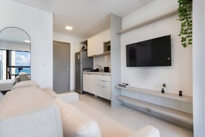 A modern kitchen with white cabinets, a built-in oven, and a large flat-screen TV mounted on the wall. - Icon Housi in Boa Viagem New 300m From the Sea By Carpediem (Recife)