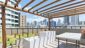 A rooftop terrace with a wooden pergola, a concrete seating area, and a view of the city skyline. - Icon Housi in Boa Viagem New 300m From the Sea By Carpediem (Recife)
