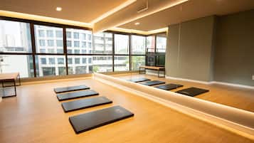 Un gimnasio moderno con suelo de madera, colchonetas de ejercicio y amplias ventanas con vistas a la ciudad.