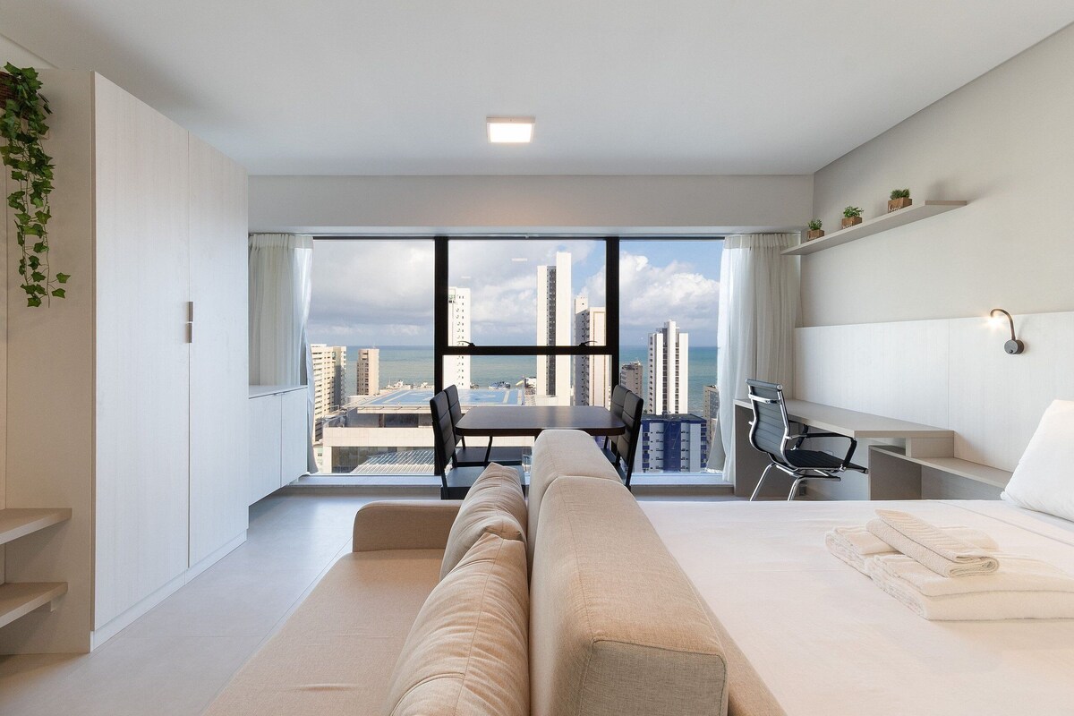 Une chambre d’hôtel moderne dotée d’une grande fenêtre, d’un canapé, d’un bureau et d’une chaise.