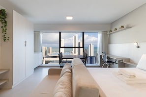 Une chambre d’hôtel moderne dotée d’une grande fenêtre, d’un canapé, d’un bureau et d’une chaise.