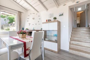 Una cuina moderna amb zona de menjador, escala i rellotge de paret.