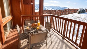 A wooden balcony with a table set for breakfast, overlooking a snowy mountain landscape. - 10m from ski slopes, 6th floor, fitness, swimming pool, sauna, hammam, balcony, tv, ski locker, 70m² (Bourg-Saint-Maurice)