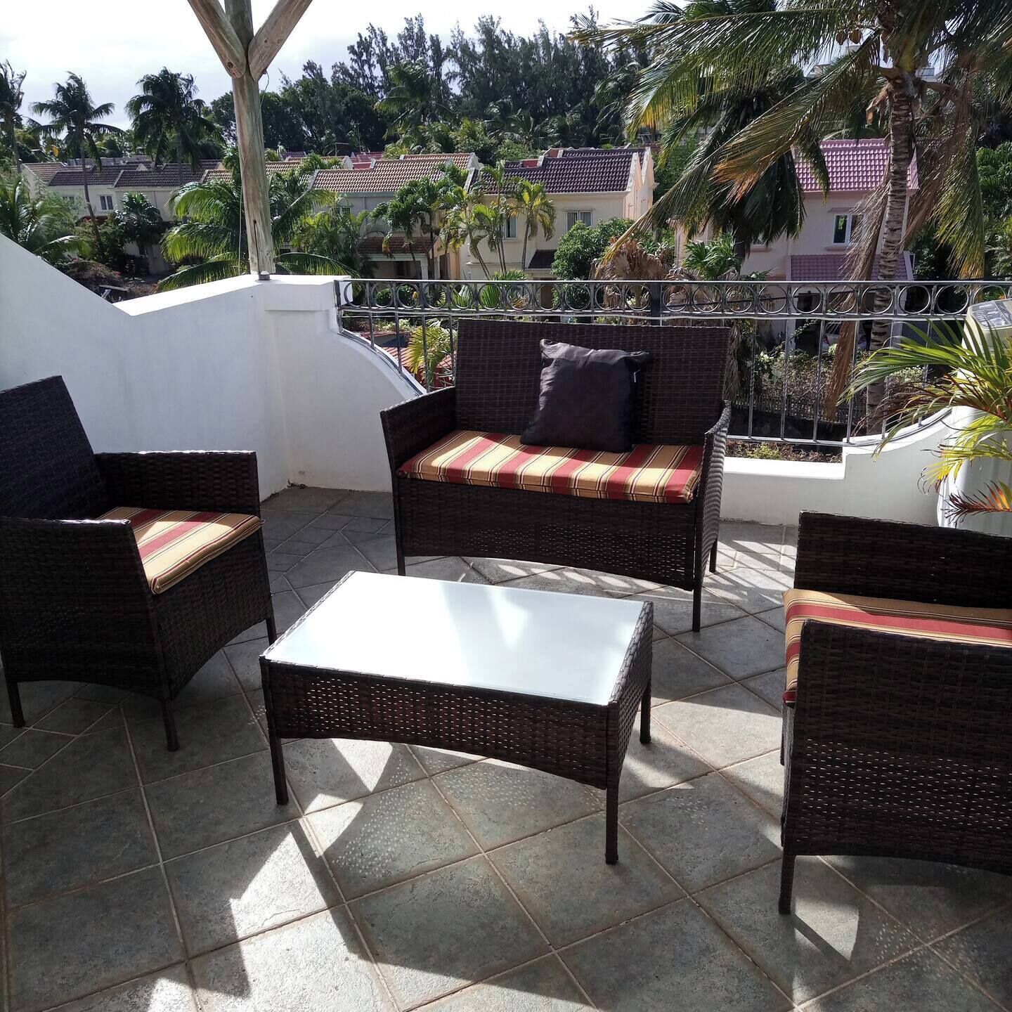 Une terrasse dotée de meubles en osier, notamment d’un canapé et de fauteuils, ainsi que d’une petite table.