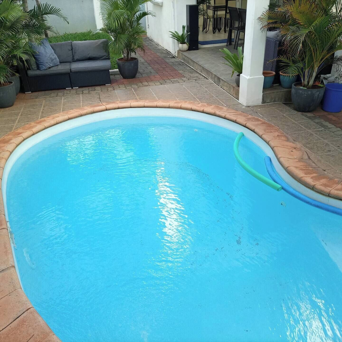 Une piscine à bord incurvé, entourée d’une terrasse carrelée.
