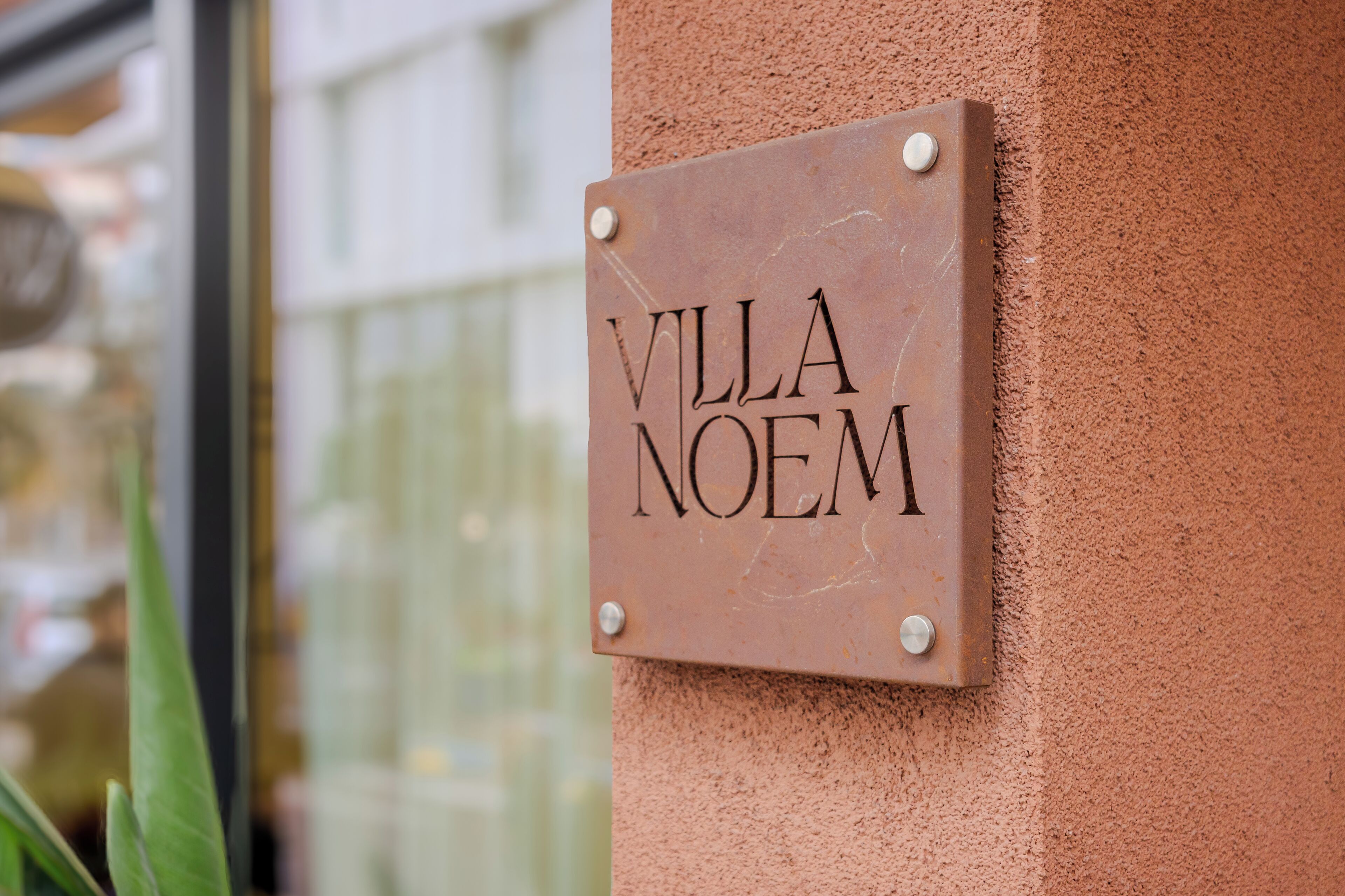 Un letrero con la inscripción "VILLA NOEM" sobre una pared con textura.