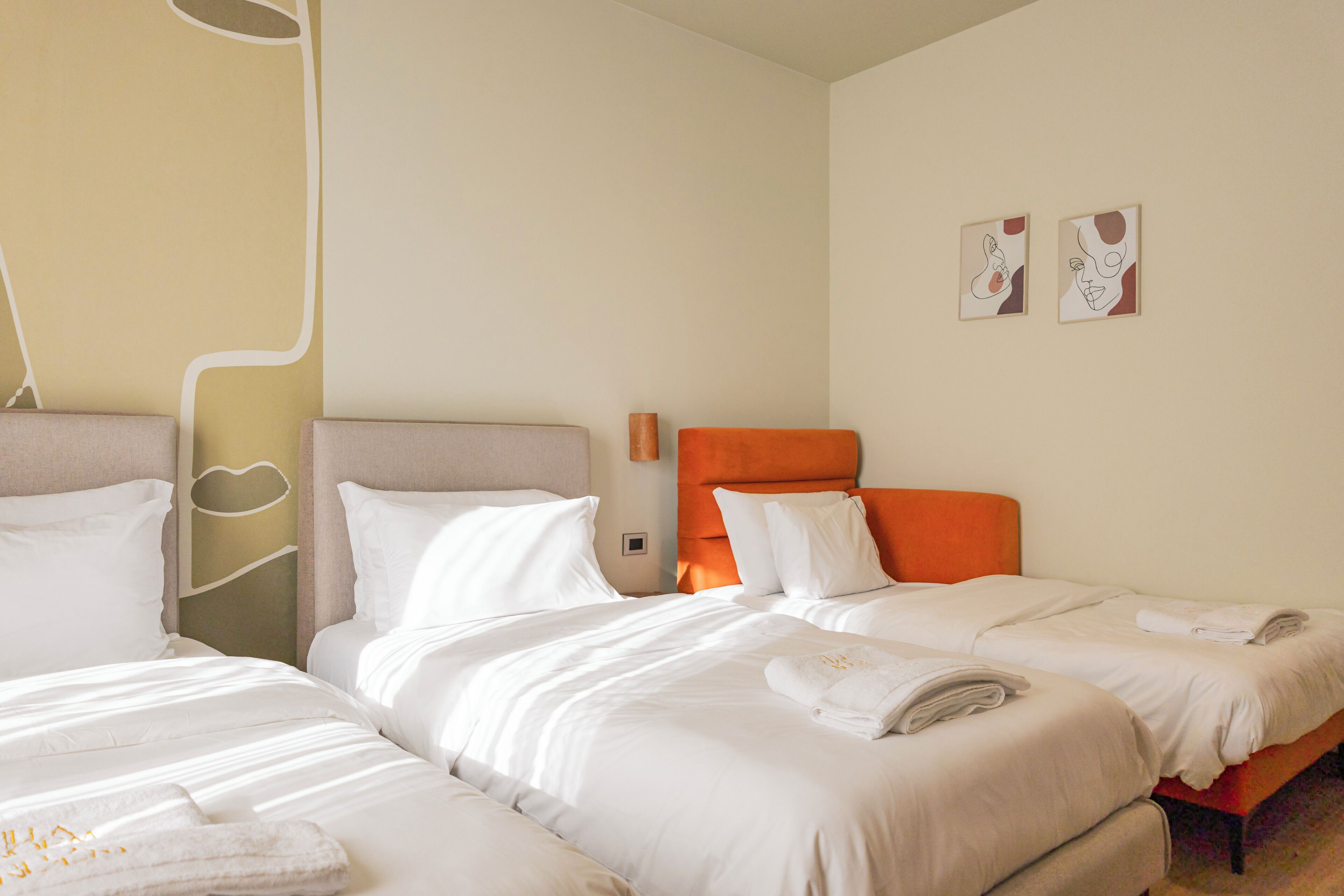 A hotel room with two beds, a large window, and a wall with abstract art.