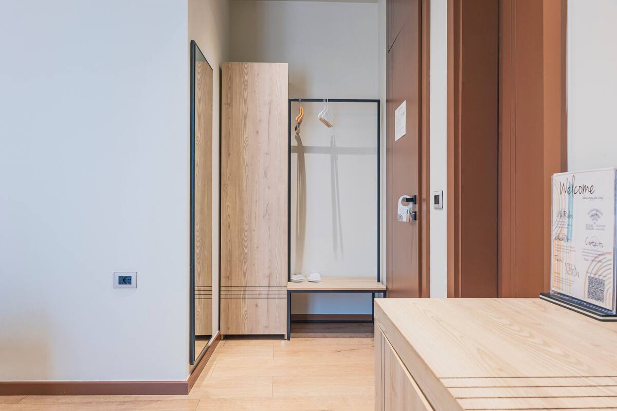 Una habitación de hotel moderna con suelo de madera, cabina de ducha de vidrio y un banco de madera.