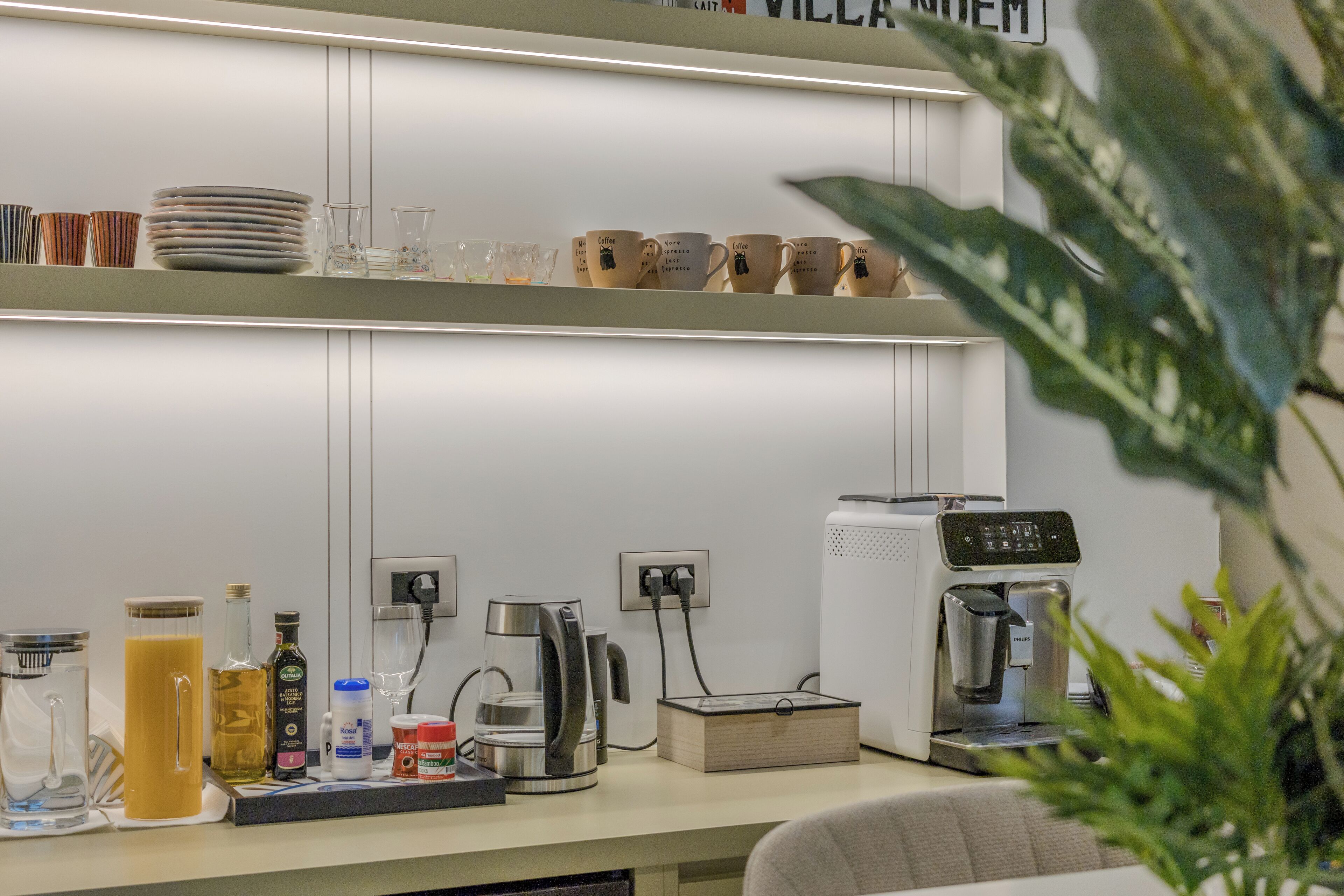 A kitchen area with a coffee machine, a kettle, and various kitchenware on the counter.