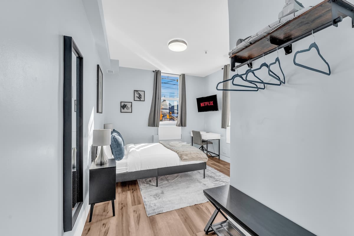 A modern bedroom with a bed, bedside table, and a desk.