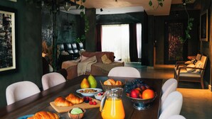 A dining area with a wooden table set for breakfast, including croissants, fruit, and a pitcher of orange juice. - Artistic Dream Mansion in Jurere International, Brazil (Florianópolis)