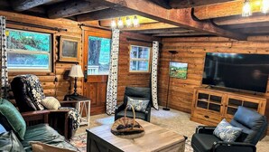 Una sala de estar acogedora con paredes de madera, un televisor grande y asientos cómodos.