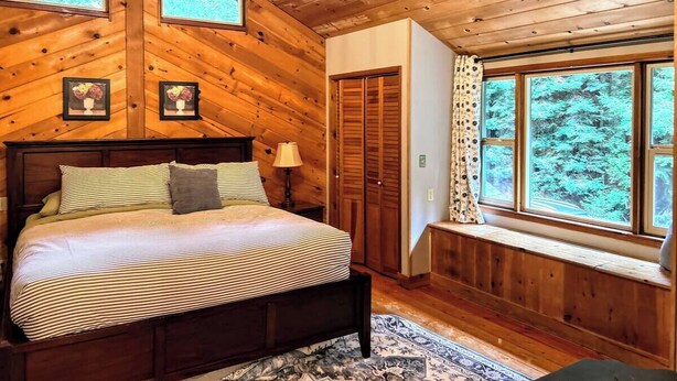 Ein Schlafzimmer in einer Holzhütte mit einem Bett, einer Kandelaber, einem Fenster und einer Tür.
