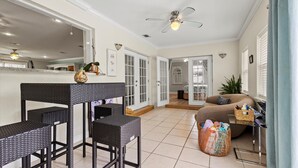 A spacious room with a dining area featuring a black wicker table and chairs, a sofa, and a small side table with a basket. - Lakehouse with Sunsets, Private Pool and Jacuzzi, 1Mi to Indian River Lagoon (Sebastian)