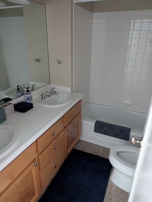 A bathroom with two sinks, a mirror, a shower, and a toilet. - Rocky Point Cottage Lakefront 3bd 2ba (Lakeport)
