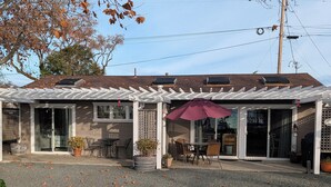 Un patio couvert avec des tables et des chaises, une pergola et un grand parasol.