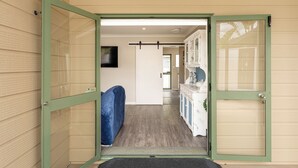 Een gang met een schuifdeur naar een badkamer met een wastafel en kastjes.